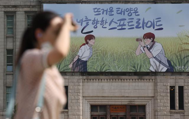 6일 뜨거운 아침 태양을 막으며 걸어가는 사람 뒤로 새단장 한 서울도서관 대형 글판이 눈에 띈다 사진연합뉴스