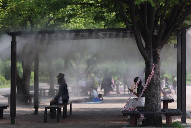 Người dân đang ngồi dưới hệ thống sương làm mát được lắp đặt trong Công viên Yeouido ở Seoul để giải nhiệt ẢnhYonhap News