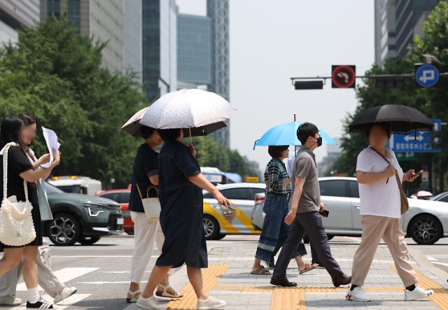 Người dân đang băng qua đường với ô che nắng tại ngã tư Gwanghwamun ở Seoul vào ngày 21 trong bối cảnh thời tiết nắng nóng trên khắp Hàn Quốc ẢnhYonhap News