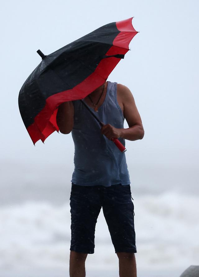제6호 태풍 카눈이 남해안에 상륙을 앞두고 있는 10일 오전 부산 해운대구 해운대해수욕장에서 한 외국인이 강풍을 피해 힘겹게 우산을 부여잡고 있다 사진연합뉴스