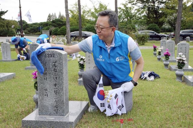 정상혁 신한은행장이 서울 동작구 국립서울현충원에서 묘역에 태극기를 꽂고 비석을 닦고 있다 사진신한은행
