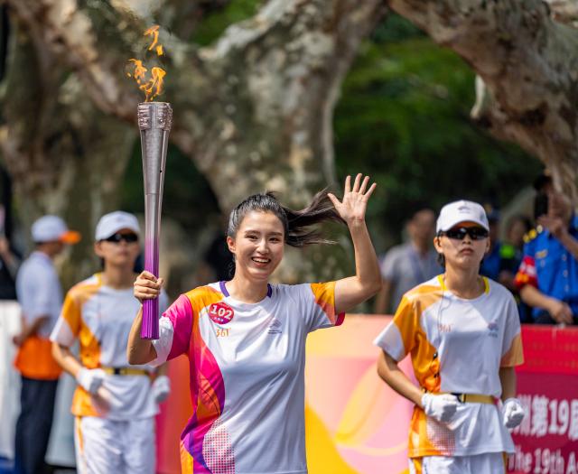 2022 항저우 아시안 게임 성화 봉송 주자가 손을 흔들며 환하게 웃고 있다 사진신화통신·연합뉴스