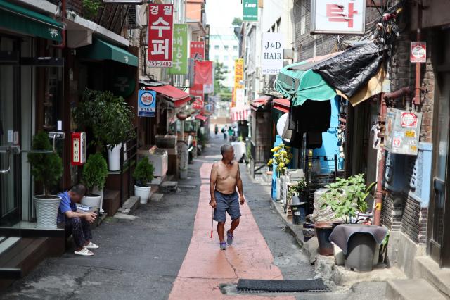 지난 8월 1일 서울 동자동 쪽방촌에서 한 시민이 상의를 탈의한 채 길을 걷고 있다