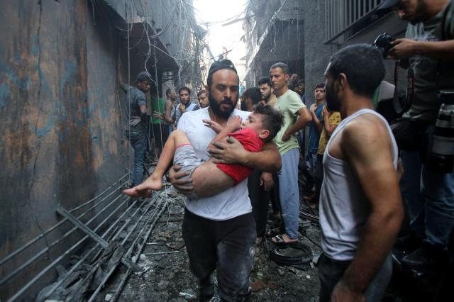 팔레스타인 무장정파 하마스와 이스라엘군 간 교전 엿새째인 10월 12일현지시간 가자지구 중심도시 가자시티에서 팔레스타인 남성이 아이를 품에 안은 채 달리고 있다 사진AFP 연합뉴스