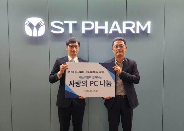 왼쪽부터 한국사회복지정보화사업소 송성현 소장과 에스티팜 이현민 경영관리본부장이 전달식에서 기념촬영 하고 있다 사진에스티팜