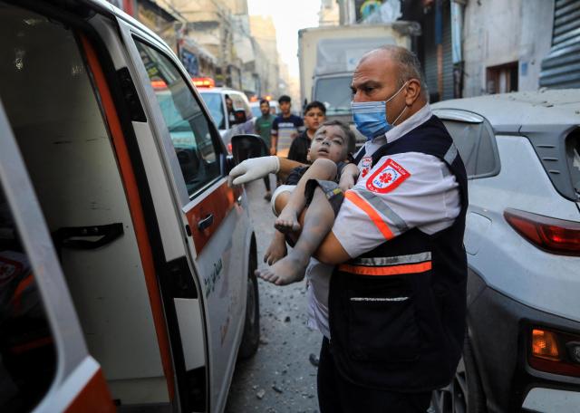 팔레스타인 무장 정파 하마스와 이스라엘 간 교전이 지속되는 가운데 10월 19일현지시간 가자지구 칸 유니스에서 한 의료진이 이스라엘 공습으로 다친 어린이를 이송하고 있다 사진로이터 연합뉴스