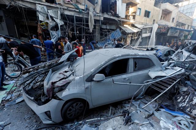 팔레스타인 무장 정파 하마스와 이스라엘 간 무력 충돌이 계속되는 가운데 19일현지시간 가자지구 칸 유니스에서 주민들이 이스라엘 공습으로 파손된 차량을 지나가고 있다 사진연합뉴스
