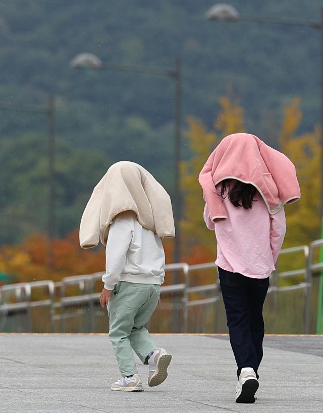 8일 오후 서울 광화문광장을 찾은 어린이들이 비가 내리자 겉옷을 머리에 쓴 채 길을 지나고 있다 사진연합뉴스