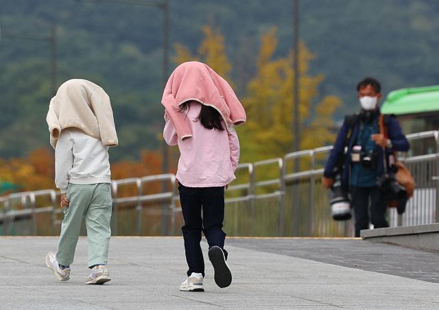 서울 광화문광장을 찾은 어린이들이 비가 내리자 겉옷을 머리에 쓴 채 길을 지나고 있다 사진연합뉴스