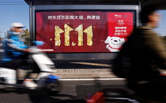 중국 베이징의 한 거리에 징둥의 광군제 홍보 포스터 앞을 시민들이 지나가고 있다 사진로이터 