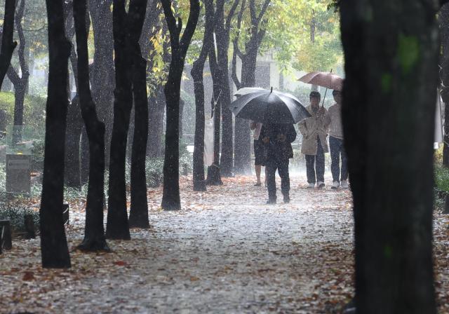 6일 오전 서울 영등포구 여의도공원 인근에서 시민들이 갑자기 비가 내리자 우산을 쓰고 걸어가고 있다 사진연합뉴스