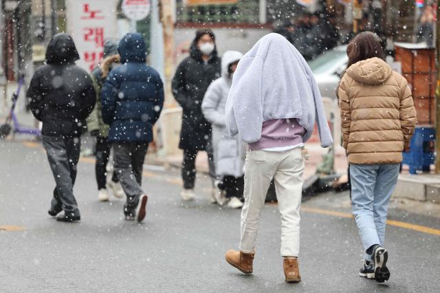 눈이 내린 17일 서울 강남구 강남역 인근에서 시민들이 겉옷으로 머리를 가리거나 외투모자를 쓰고 걷고 있다 사진연합뉴스