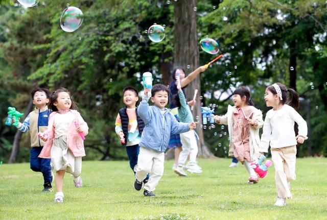 Các em nhỏ đang vui chơi với bong bóng xà phòng trên bãi cỏ của Đại học Quốc gia Chonnam ở Buk-gu Gwangju Ảnh chụp ngày 352023 ẢnhYonhap News