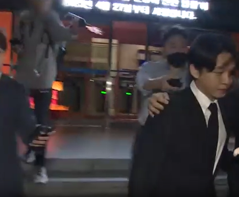 지난해 5월 배우 유아인이 서울 마포구 경찰서에서 나오는 모습 뒤로 회색 후드티와 청바지를 입은 남성이 커피를 뿌리고 있다 사진연합뉴스TV