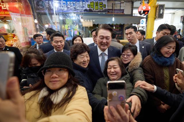 윤석열 대통령이 설 명절을 앞두고 8일 서울 광진구 중곡제일시장을 찾아 시민들의 셀카 촬영 요청에 응하고 있다 사진연합뉴스