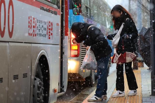 전국 곳곳에서 비와 눈이 내린 5일 오후 서울 광화문네거리 인근 버스 정류장에서 한 시민이 버스를 탑승하기 전 눈을 털고 있다 사진연합뉴스 
