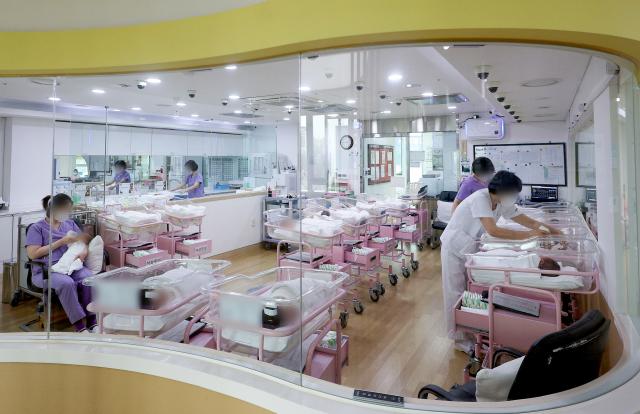 Các y tá và các nhân viên y tế đang chăm sóc trẻ sơ sinh tại một trung tâm chăm sóc sau sinh ở Seoul ẢnhYonhap News