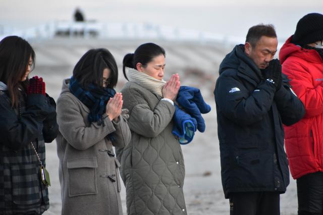 동일본대지진 13주기를 맞은 11일 아침 일본 북부 센다이 해변에서 사람들이 희생자를 위해 기도하고 있다사진지지통신EPA연합뉴스