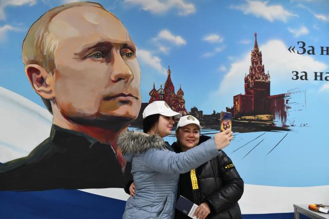 러시아가 점유하고 있는 우크라이나 지역의 도네츠크에서 유권자들이 투표 후 블라디미르 푸틴 러시아 대통령의 그림 앞에서 사진을 찍고 있다사진EPA연합뉴스