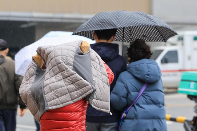 최근 서울 시내 한 대학병원에서 겉옷으로 비를 막는 시민이 이동하는 모습 사진연합뉴스