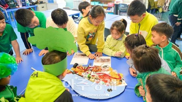 4학년 여학생이 1학년 학생들에게 본인의 콜라주 작품에 대해 설명하고 있다사진중국 옌타이요화국제학교