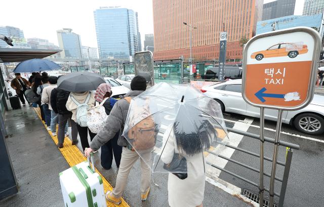Trời mưa xe buýt đình công khiến không ít người dân phải lựa chọn taxi để có thể di chuyển tới văn phòng công sở Hình ảnh hàng người xếp hàng chờ bắt taxi gần ga Seoul vào sáng ngày 2832024 ẢnhYonhap News