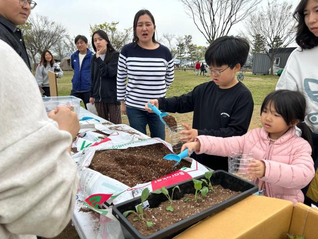 어린이 캠핑객들이 재활용 플라스틱 용기에 식물 모종을 심고 있다사진밀양시시설관리공단