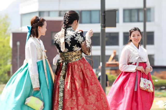 Tourists dressed in hanbok traditional Korean clothing take pictures at Songhyeon Green Plaza in central Seoul on April 12 2024 AJU PRESS Kim Dong-woo