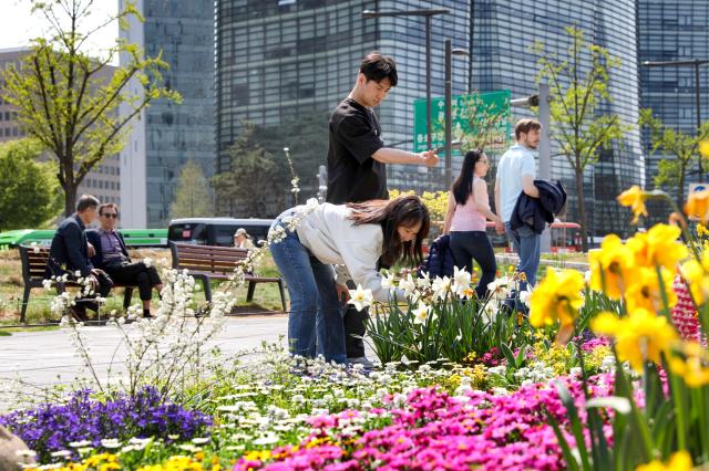 A couple takes photos of flowers while enjoying a spring outing at Songhyeon Green Plaza in central Seoul on April 12 2024 AJU PRESS Kim Dong-woo