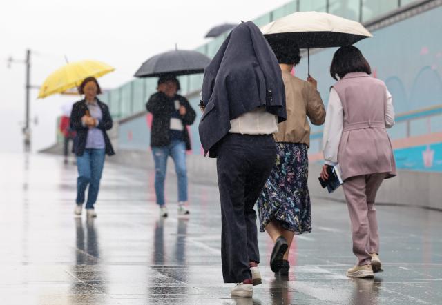 비가 내린 15일 오후 서울 종로구 광화문광장에서 한 시민이 자켓으로 머리를 가린 채 뛰고 있다 사진연합뉴스