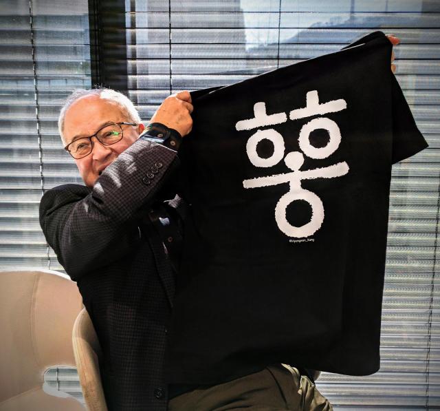 Sung Ki-hak chairman of outdoor apparel maker Youngone Corp holds a T-shirt bearing old Korean letters Courtesy of photojournalist Hyungwon Kang