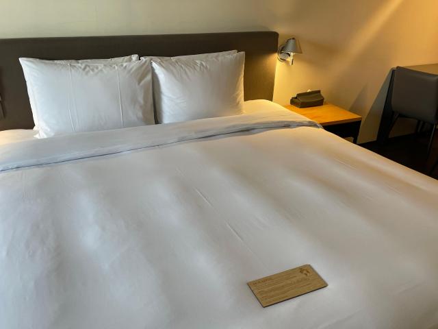 글래드 호텔 침대 위 나무로 제작된 침구와 수건 세탁 교체 안내문이 놓여 있다 사진김다이 기자