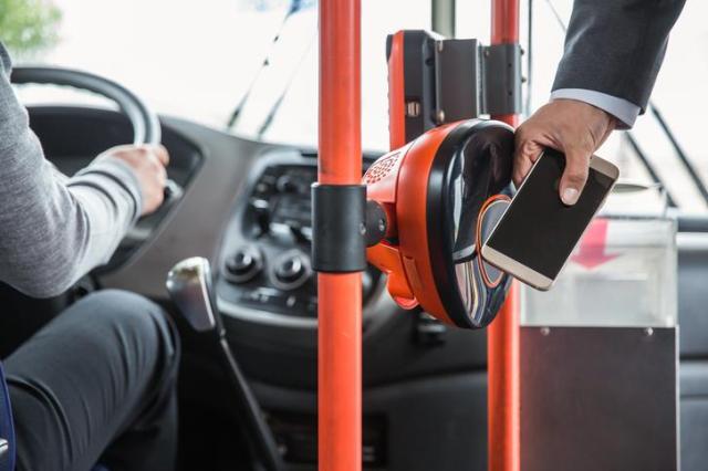 A man is using a transit card application to ride a bus