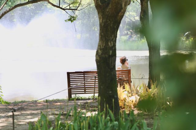 A woman sits on a bench in front of the fountain at Seoul Forest