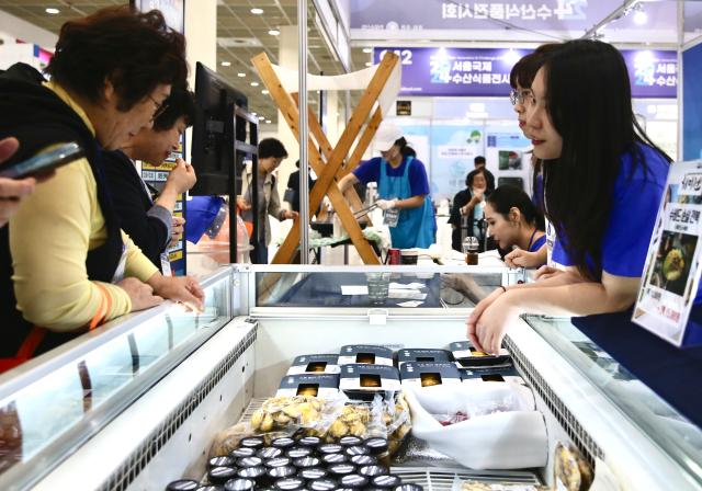 A booth staffer talks to visitors at the Seoul Seafood Show at COEX on May 16 2024 AJU PRESS Han Jun-gu