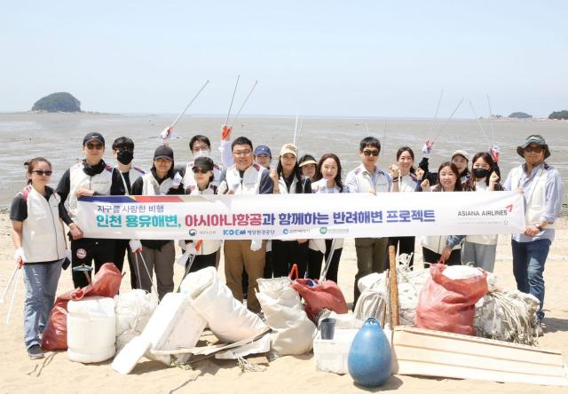 아시아나항공 직원들이 23일목 인천 용유해변에서 정화 활동을 마친 후 기념 사진을 찍고 있다
