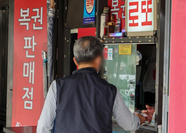 한 시민이 서울 시내 복권판매점에서 복권을 구매하고 있다 사진연합뉴스