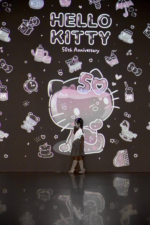 A child poses in front of a beam projector exhibit at the Hello Kitty 50th Anniversary Special Exhibition hold at the DDP on June 3 2024 AJU PRESS Han Jun-gu