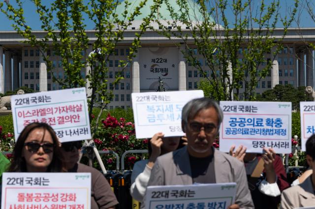 In the background behind the protesting activists a banner celebrating the opening of the 22nd National Assembly hangs on the National Assembly building at Yeoui-do Seoul on June 4 2024 AJU PRESS Park Jong-hyeok