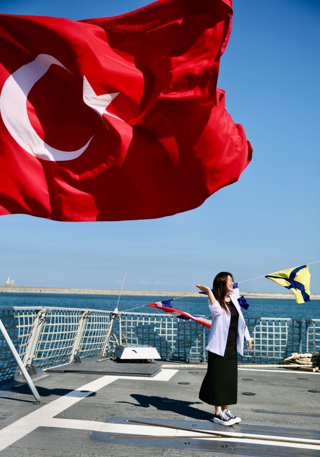 A woman takes a commemoration photo in front of the Turkish flag on the Türkiye’s corvette-class warship TCG Kinaliada arriving at Busan Port on June 4 2024 AJUPRESS Han Jun-gu