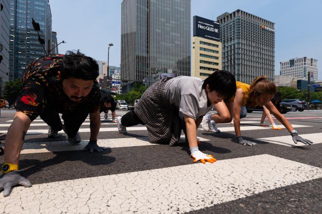 Participants crawl on all fours across a crosswalk during the performance at Gwanghwamun Square in Jongno Seoul on June 5 2024 AJU PRESS Park Jong-hyeok