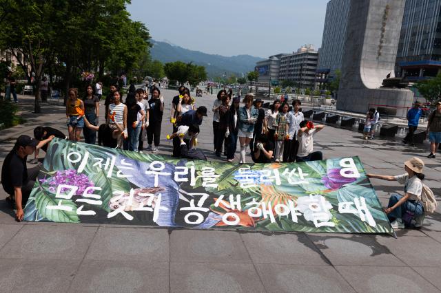 Participants in the performance hold up a banner that reads Now is the time for us to coexist with everything around us AJU PRESS Park Jong-hyeok