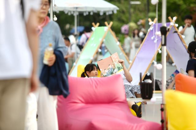A visitor and a child read books during the Seoul Outdoor Library event at Gwanghwamun Square in Seoul on June 7 2024 AJU PRESS Han Jun-gu
