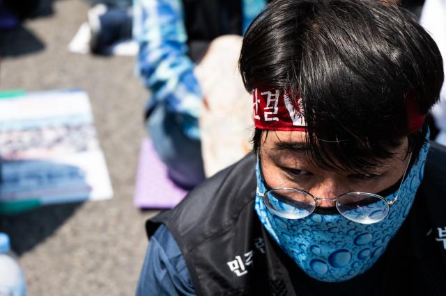 A participant at the 613 National Street Vendors Rally endures the sweltering heat in front of the Korea Development Bank in Yeongdeungpo district Seoul on June 13 2024 AJU PRESS Park Jong-hyeok