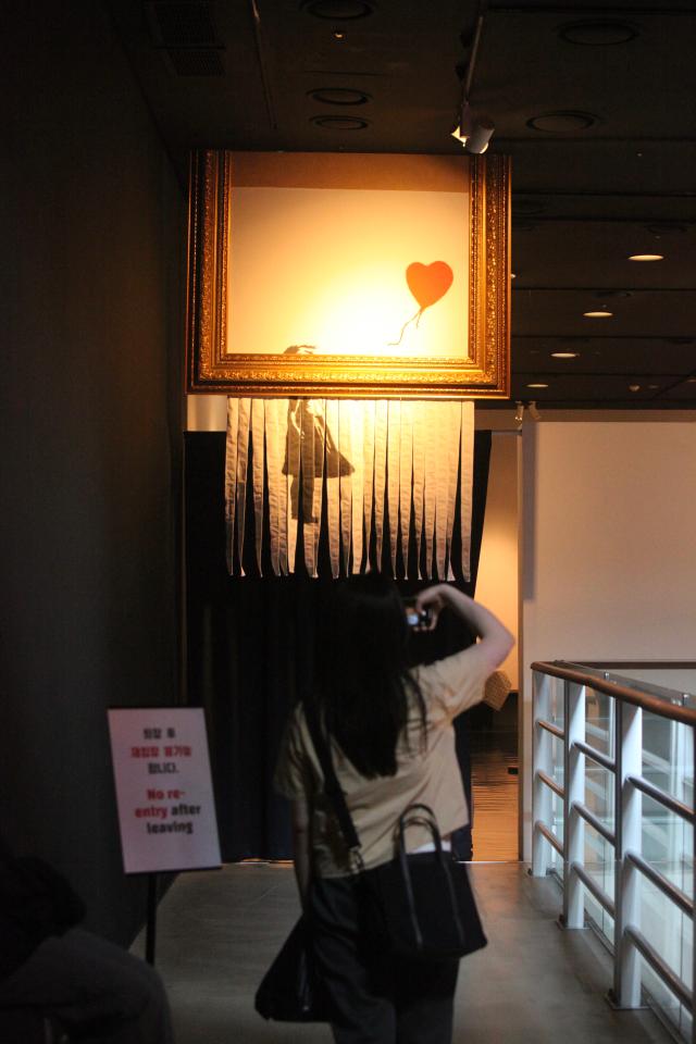 A visitor takes a photo of an artwork at the REAL BANKSY Banksy is NOWHERE exhibition AJU PRESS Han Jun-gu