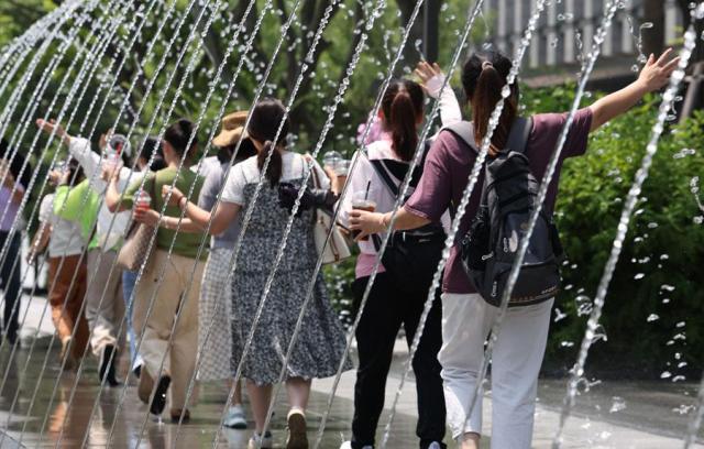 Pedestrians pass through a fountain tunnel at Gwanghwamun Square in central Seoul on June 19 2024 Yonhap