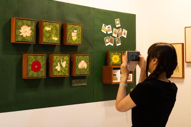 A visitor take a photo of exhibited artwork with a smartphone at The 6th Korea Minhwa Art Fair SETEC Gangnam Seoul June 20 2024 AJU PRESS Park Jong-hyeok