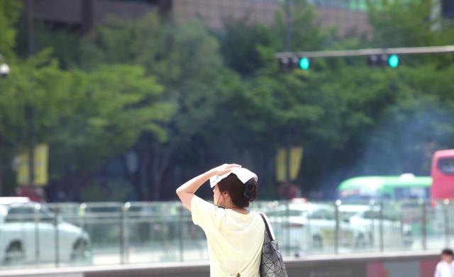 1 A woman puts a cloth on her head at Gwanghwamun Square June 21 2024 AJU PRESS Han Jun-gu