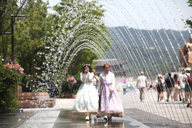 People walk under the fountain at Gwanghwamun Square June 21 2024