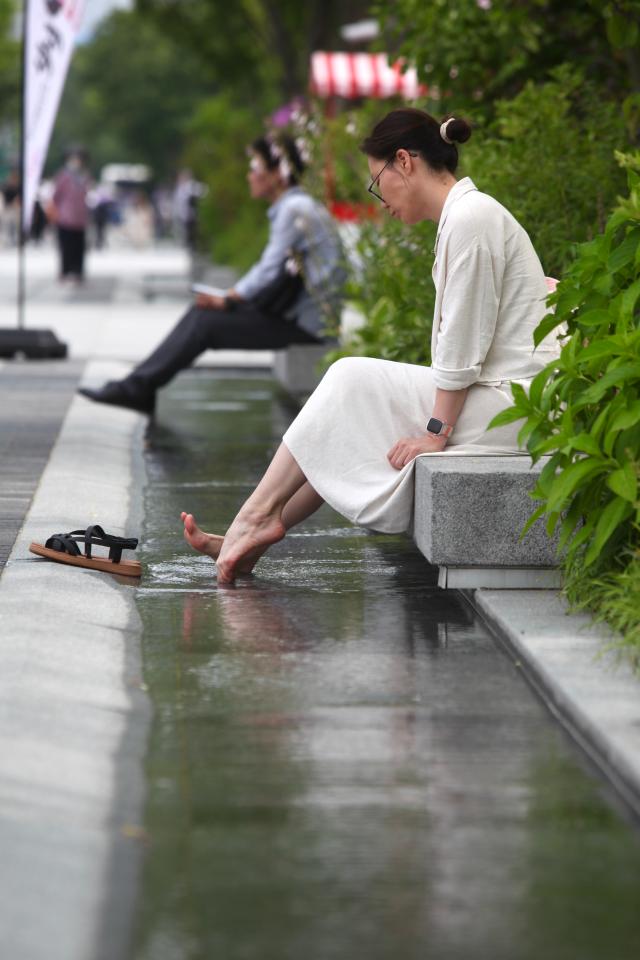 A woman soaks her feet in the flowing water at Gwanghwamun Square June 21 2024 AJU PRESS Han Jun-gu